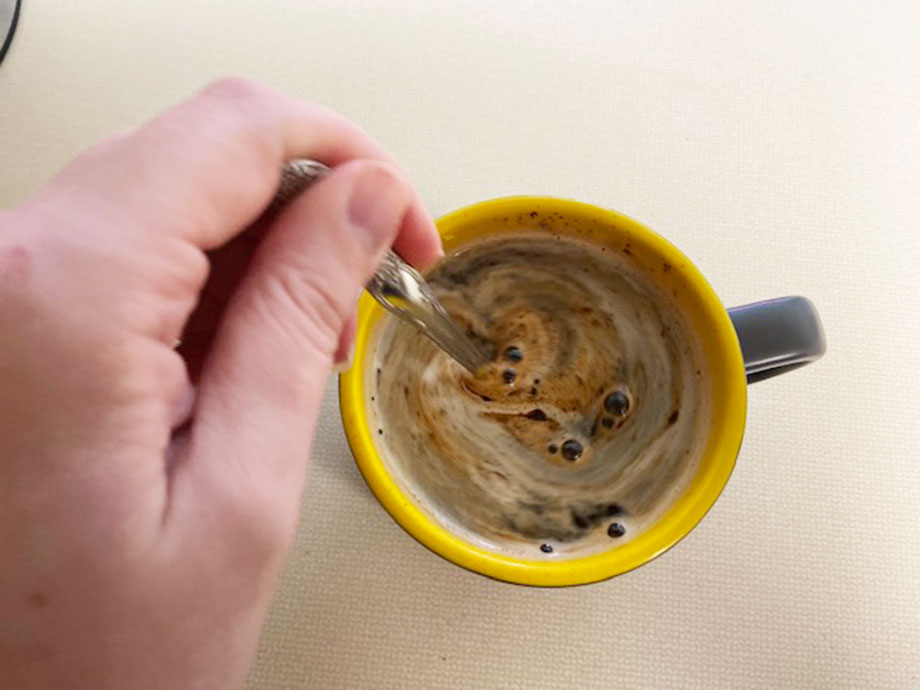 A hand stirs one of the best mushroom coffees