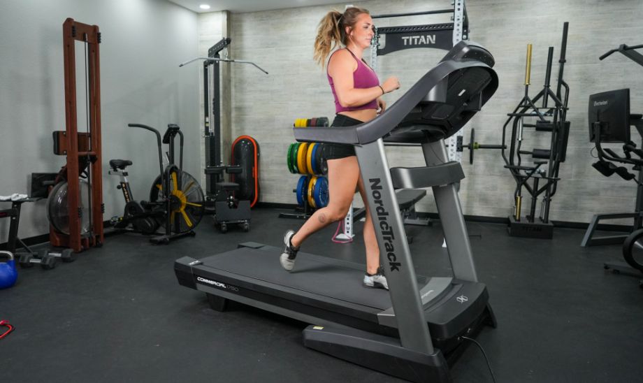 A woman running on the NordicTrack Commercial 1750 treadmill in a room full of different workout equipment.